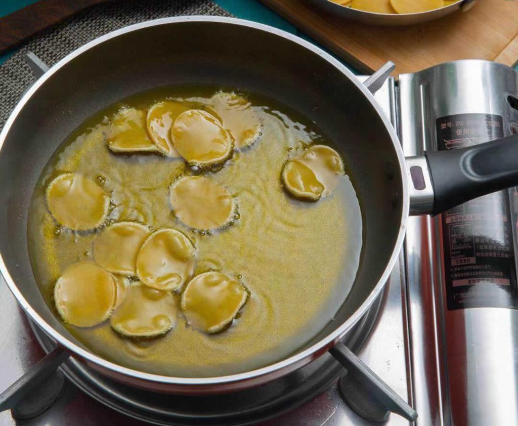 Disques de pâte pani puri plongés dans l’huile chaude, début de la friture des coques croustillantes