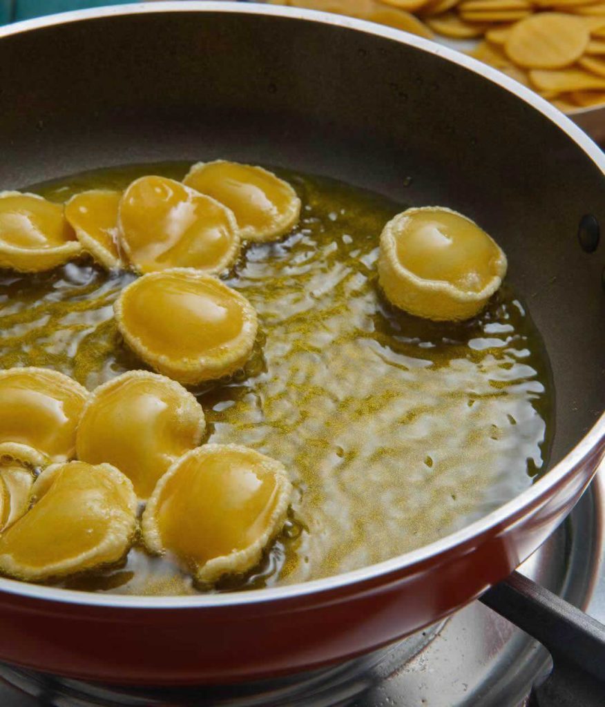 Coques pani puri qui gonflent dans l’huile chaude pendant la cuisson traditionnelle indienne