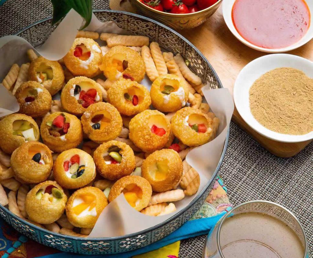 Préparation des pani puri garnis avec sauces, légumes et pois chiches – spécialité street food indienne