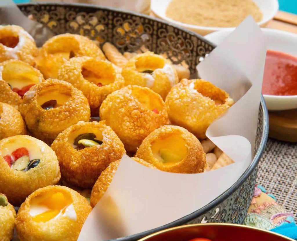 Plateau de pani puri prêts à déguster avec garniture et sauces traditionnelles indiennes